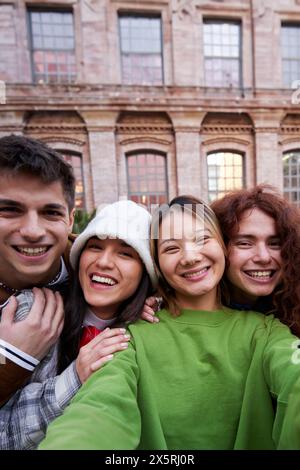 Multiracial group of cheerful friends taking selfie together outdoors at university.  Stock Photo