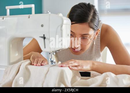 Tailor, sewing machine and woman in apartment for small business, fashion design and working. Female seamstress or sewer, fabric and creativity in Stock Photo