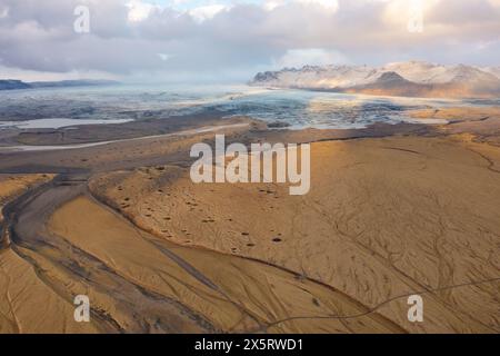 Cloudy sunset drone view mountain peaks covered with snow. Volcanic valley below. East Iceland. Stock Photo