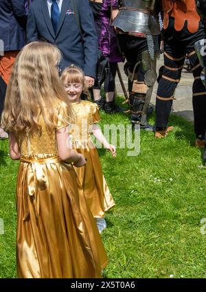 Two young bridesmaids or flower girls in matching gold dresses playing outside after a wedding in the Unitarian church Framlingham Suffolk Stock Photo