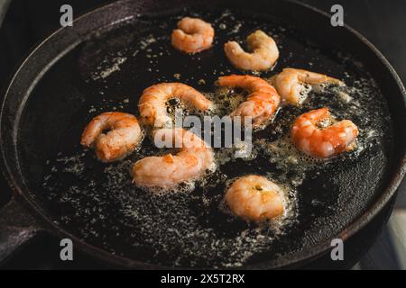 King prawns are fried in boiling oil in a cast-iron skillet. Mediterranean cuisine. Selected focus. High quality photo Stock Photo