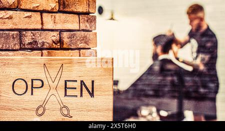 Open sign crafted with on wooden board in window. Bearded man getting haircut. Barbershop salon. Open barder shop. Hairdresser or barber Stock Photo
