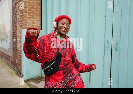 Smiling young woman wearing red dancing outdoors Stock Photo
