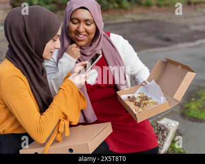 Woman using smart phone during lunch in park with friend Stock Photo