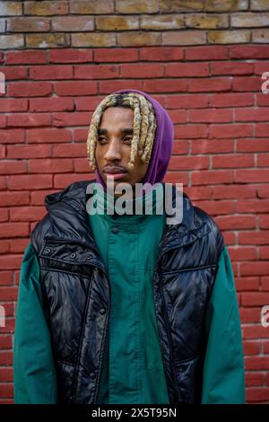 Young man standing against brick wall Stock Photo