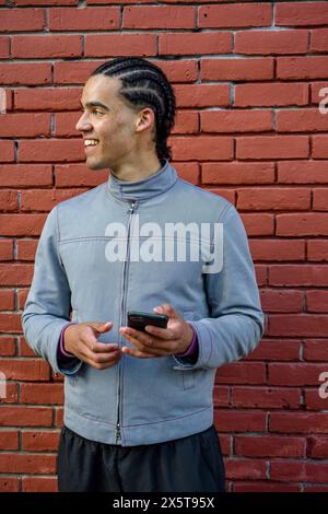 Smiling young man using phone outdoors Stock Photo