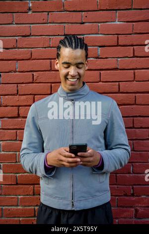 Smiling young man using phone outdoors Stock Photo