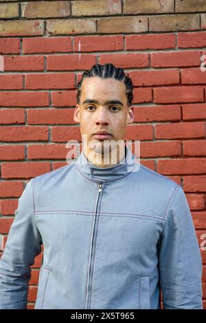 Portrait of young man standing against brick wall Stock Photo