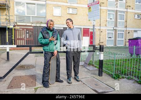Young male friends using phone outdoors Stock Photo