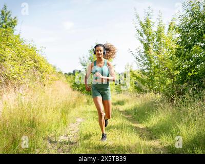 Woman running in meadow on sunny day Stock Photo