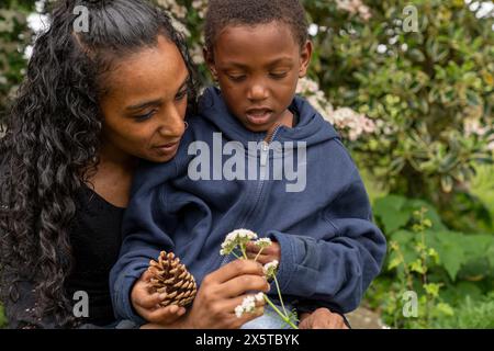 Mother and son looking at flower and pine cone Stock Photo