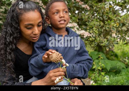Mother and son holding flower and pine cone Stock Photo