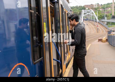 Young man talking by phone while entering to tram Stock Photo