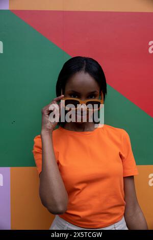 Portrait of smiling young woman in orange sunglasses Stock Photo