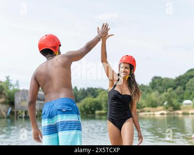 Woman and man giving high-five by lake Stock Photo