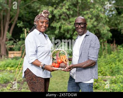 Portrait of mature couple holding vegetables from garden Stock Photo