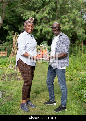 Portrait of mature couple holding vegetables from garden Stock Photo