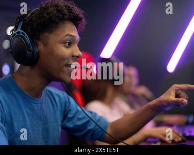 Excited man playing video games with friends in gaming club Stock Photo