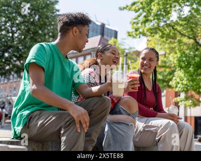 Friends laughing while drinking smoothies in city Stock Photo