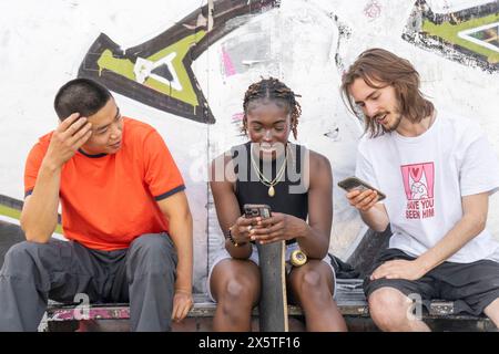 Group of young friends with skateboards using phones Stock Photo