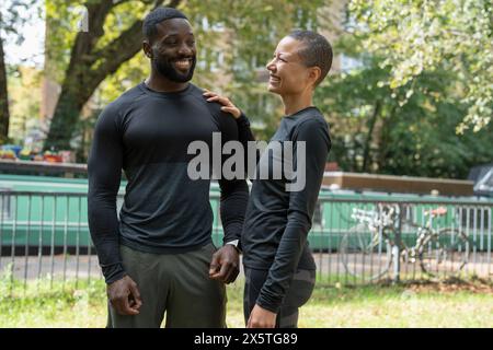 Smiling athletic man and woman standing in park Stock Photo