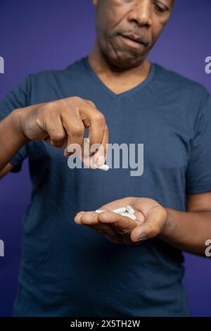 Man taking medicine against purple background Stock Photo