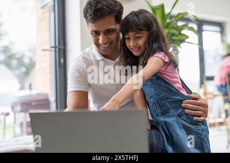 Father sitting with daughter and using laptop Stock Photo