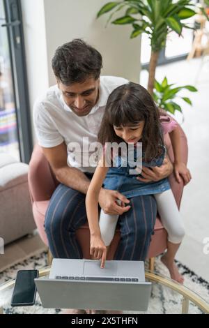 Father sitting with daughter and using laptop Stock Photo