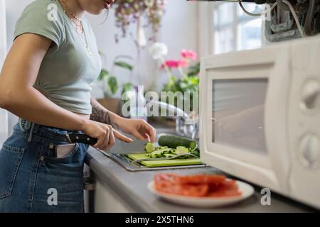 Midsection of young woman chopping vegetables in kitchen Stock Photo