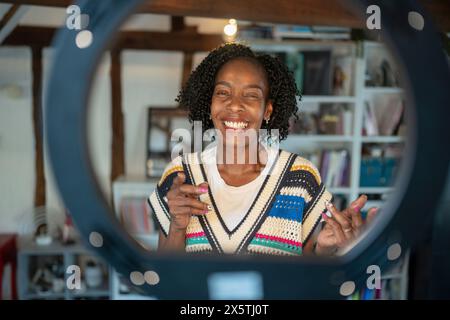 Smiling woman standing in front of ring light at home Stock Photo