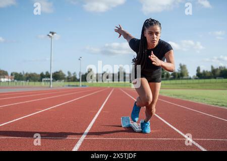 Female athlete sprinting off starting line at stadium Stock Photo - Alamy