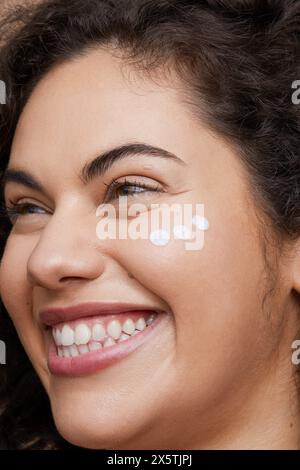 Close-up of young woman applying face cream Stock Photo