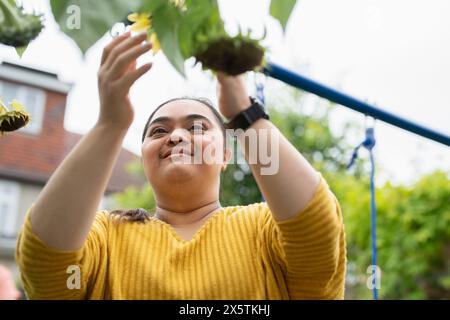 Young woman with down syndrome touching flower in garden Stock Photo