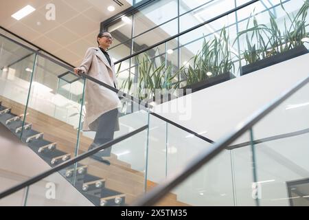 Non binary office worker walking on steps Stock Photo