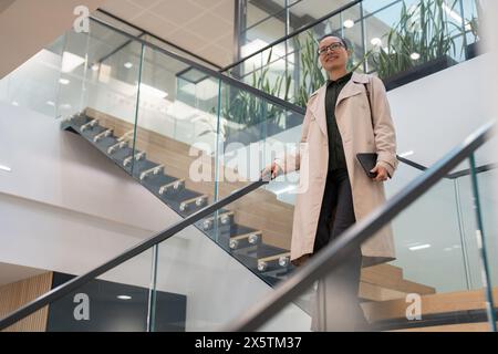 Non binary office worker walking on steps Stock Photo