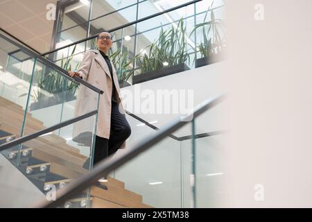 Non binary office worker walking on steps Stock Photo