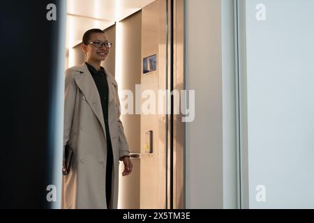 Non binary office worker walking in hallway Stock Photo