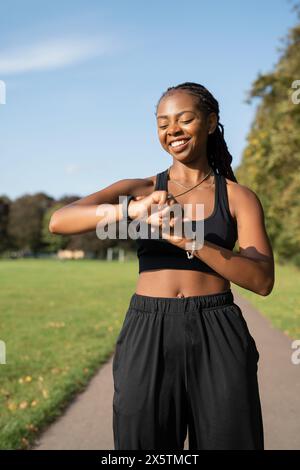 Smiling young woman checking time after jogging Stock Photo