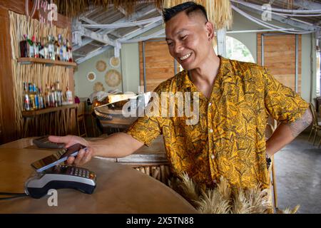 Man paying with smart phone in beach bar Stock Photo
