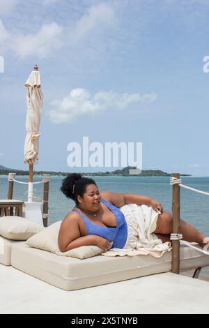 Young woman relaxing on sun lounger near bay Stock Photo