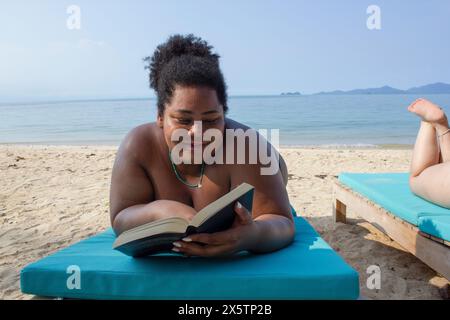 Young woman relaxing and reading on beach Stock Photo