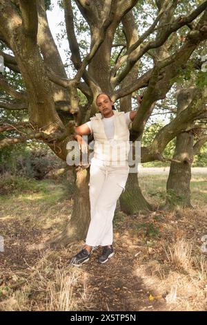 Portrait of young woman leaning on tree Stock Photo