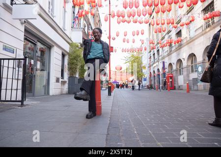 Young woman sitting on bollard in Chinatown Stock Photo