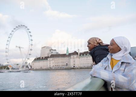 UK, London, Female tourists in hijabs looking at London Eye over River Thames Stock Photo