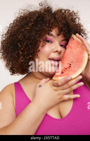 Brunette woman holding slice of watermelon, looking at camera Stock Photo