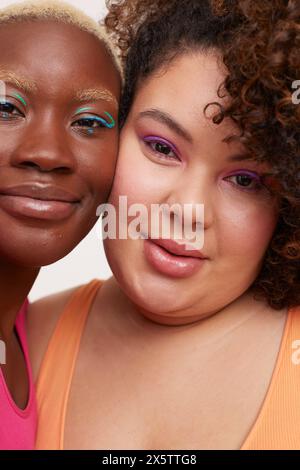 Portrait of two young women wearing make up, cheek to cheek Stock Photo
