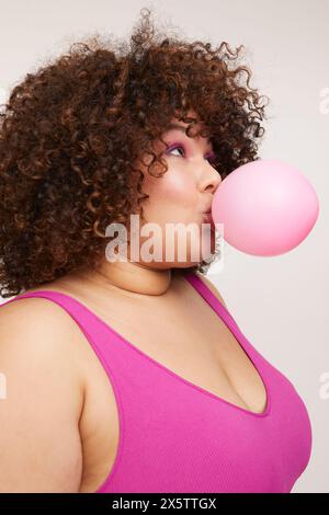 Brunette woman blowing pink balloon Stock Photo