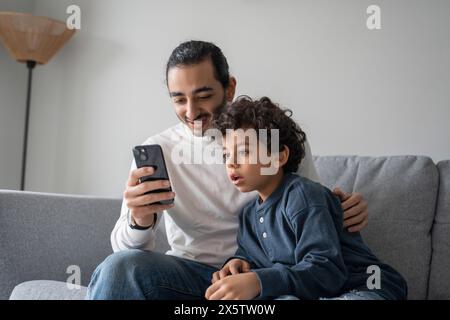 Father and son (6-7) using smart phone at home Stock Photo