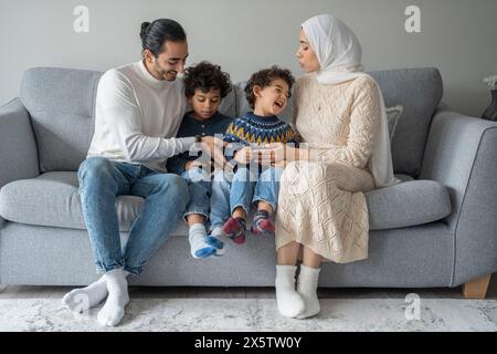 Parents and sons (2-3, 6-7) relaxing on sofa Stock Photo