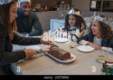 Woman cutting chocolate Yule log cake at Christmas dinner table Stock Photo